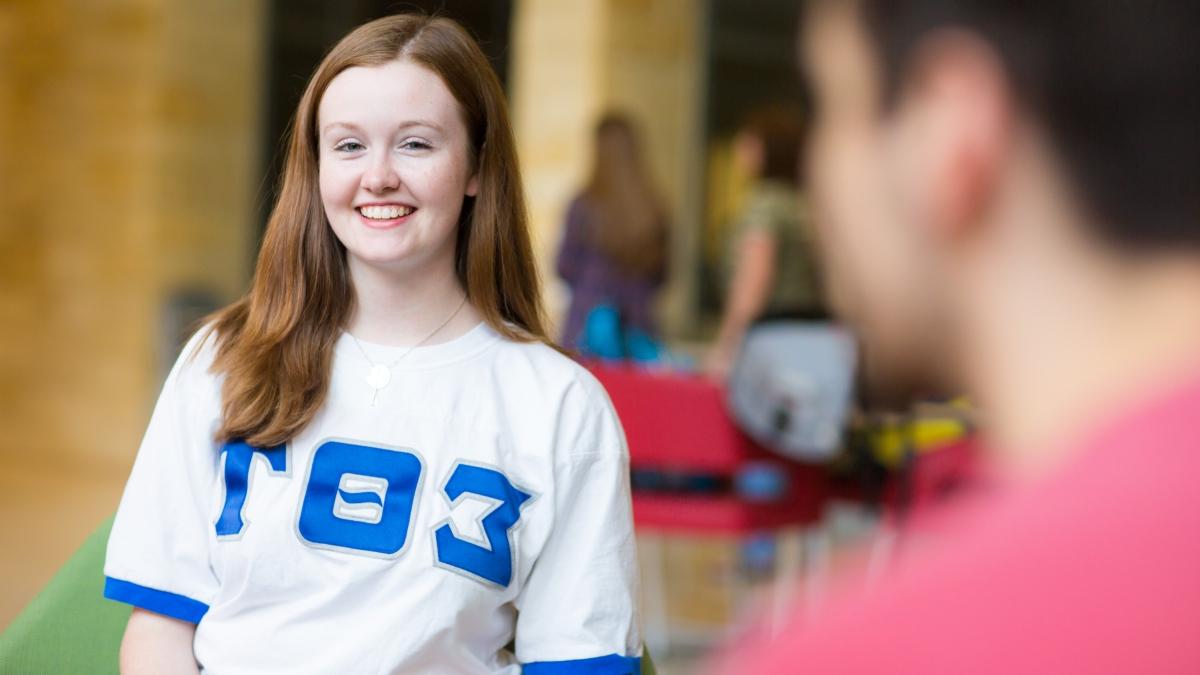 a woman in a Sigma 的ta Tau jersey smiles